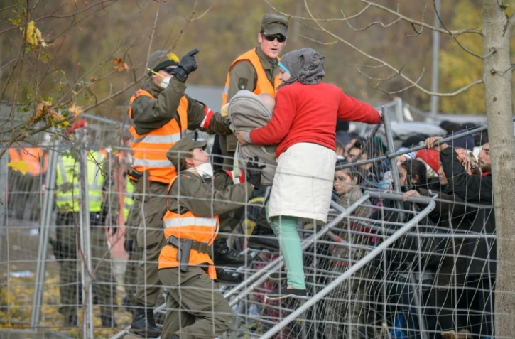 Des militaires autrichiens empêchent une femme tenant son bébé dans les bras de passer un grillage alors qu'elle tente de traverser la frontière austro-slovène depuis Sentilj, en Slovénie, le 30 octobre 2015