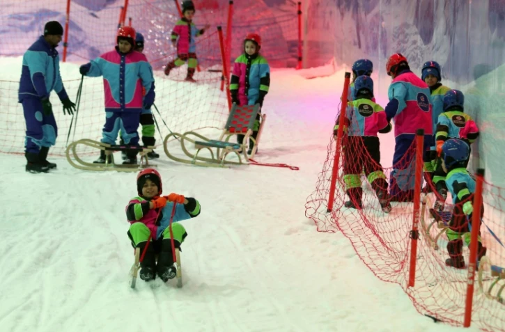 Des jeunes Saoudiens glissent sur des pentes enneigées installées dans un parc à neige à Ryad, le 20 juillet  2016 