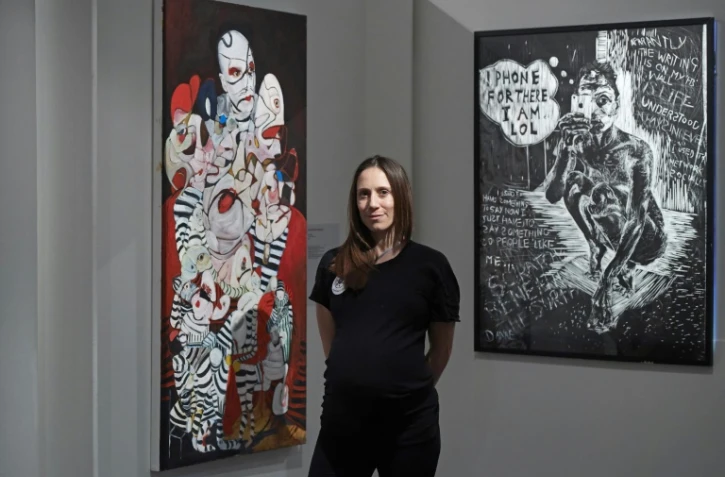 L'artiste britannique Dannielle Hodson pose devant ses oeuvres à Sotheby's à Londres, le 16 janvier 2018
