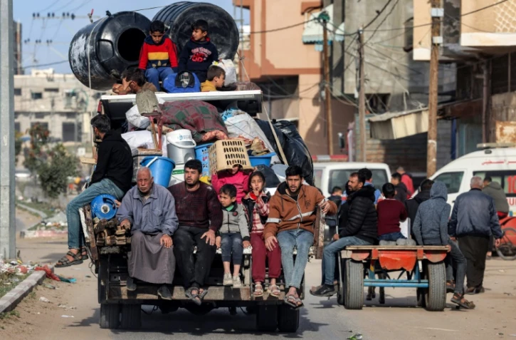Les membres d'une famille palestinienne à l'arrière d'un véhicule chargé de leurs affaires, quittent Rafah, dans le sud de la bande de Gaza, face à la menace d'une offensive militaire israélienne sur la ville, le 12 février 2024