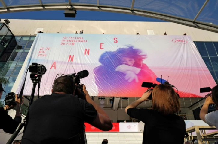 Des employés installent l'affiche officielle du 78e Festival de Cannes sur la façade du Palais des Festivals à Cannes, dans le sud-est de la France, le 11 mai 2025