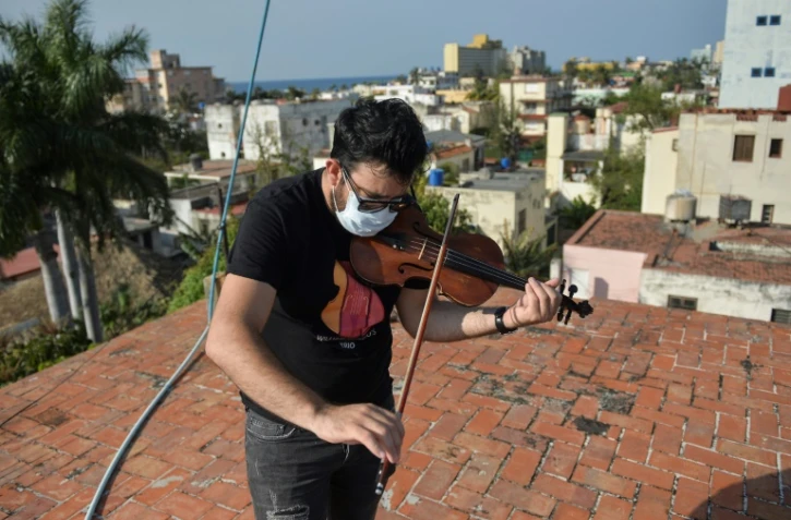 William Roblejo joue du violon sur le toit de sa maison, le 15 avril 2020 Ă La Havane, Ă Cuba