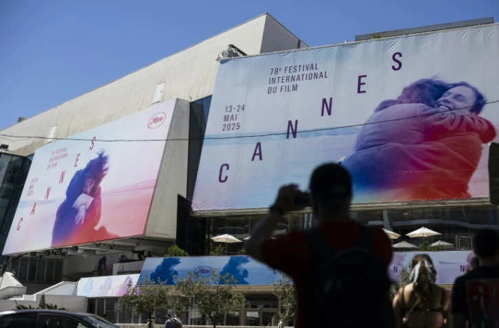 Un piéton prend une photo des affiches de la 78e édition du Festival de Cannes devant le Palais des Festivals à Cannes, dans le sud de la France, le 12 mai 2025
