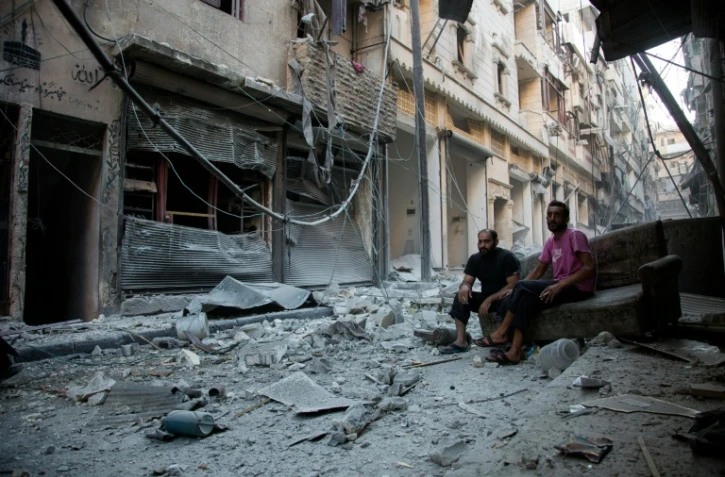 Des Syriens au milieu des décombres du quartier pro-régime de Karm al-Jabal ciblé par une frappe aérienne le 18 septembre 2016 à Alep