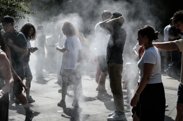 Des personnes se rafraîchissent au milieu de brumisateurs à Paris, le 1er juillet 2025, en période de canicule