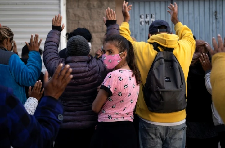 Prières dans une rue proche d'un abri pour migrants au passage d'El Chaparral, près de Tijuana, au nord du Mexique, le 14 avril 2021
