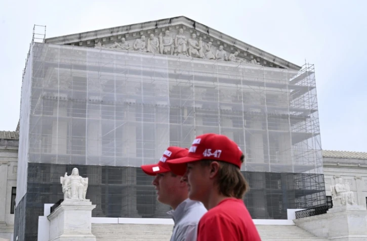 Deux hommes portant des casquettes "Make America Great Again" (MAGA, Rendre sa grandeur à l'Amérique), passent devant la Cour suprême des Etats-Unis, à Washington, le 27 juin 2025