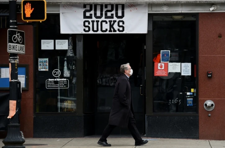 Un homme portant un masque passe devant un restaurant orné d'une bannière "2020 craint", le 18 décembre 2020 à Arlington, en Virginie (Etats-Unis)