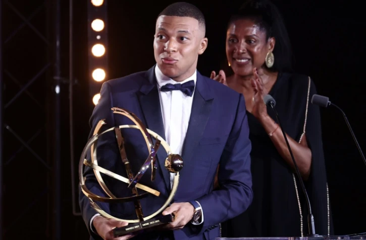 Kylian Mbappé avec le trophée UNFP de meilleur joueur de la saison de Ligue 1 que vient de lui remettre Marie-Josée Pérec, derrière lui, le 13 mai 2024 à Paris