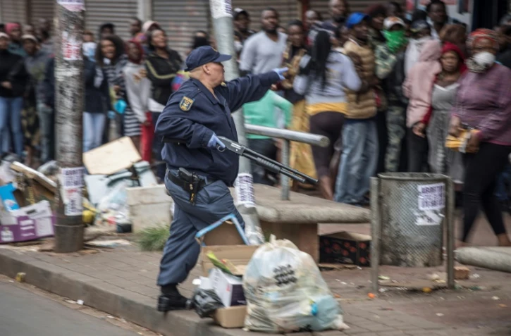 Un policier tient un fusil pour disperser la foule  devant un supermarché, le 28 mars 2020 à Johannesburg, en Afrique du Sud