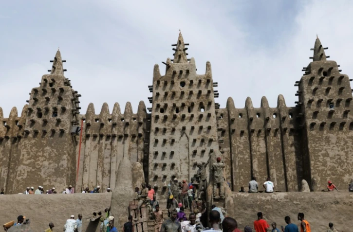 Des personnes utilisent du banco, un enduit de terre, pour le crépissage annuel de la grande mosquée de Djenné le 12 juin 2025