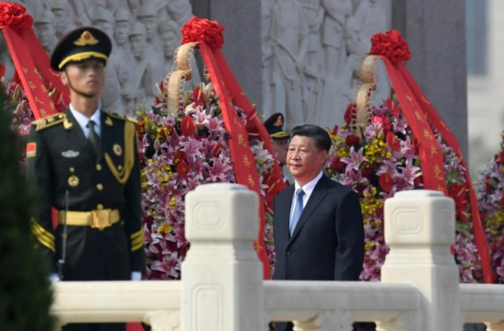 Le président chinois Xi Jinping (c) dépose une gerbe lors d'une cérémonie en hommage aux Héros du peuple, place Tiananmen à Pékin, le 30 septembre 2019