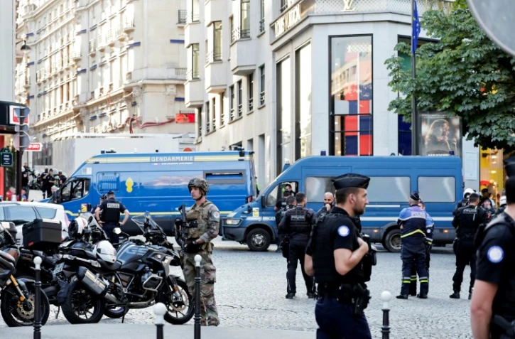 Des policiers, des gendarmes et un soldat sécurisent la zone devant une boutique Louis Vuitton après qu'un homme a attaqué un policier avec un couteau, sur les Champs-Elysées, à Paris, le 18 juillet 2024