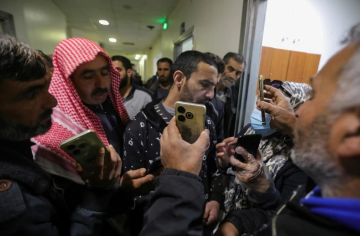 Des Syriens à la recherche de leurs proches disparus montrent leurs photos à un homme anciennement détenu à la prison de Saydnaya, alors qu'il arrive pour un contrôle à l'hôpital de Damas, le 14 décembre 2024