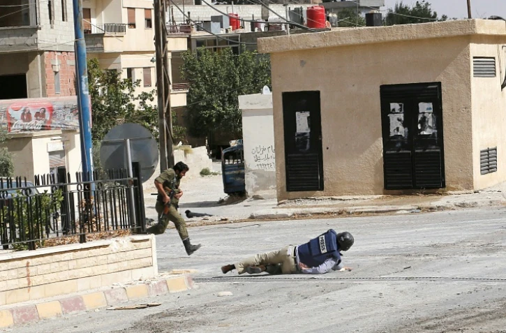 Sammy Ketz, grand reporter à l'AFP, à terre pendant des échanges de tirs dans la ville de Maaloula en Syrie, alors qu'un militaire syrien traverse en courant, le 18 septembre 2013