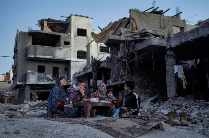 Une famille palestinienne rompt le jeûne du ramandan dans les ruines de sa maison à Deir el-Balah, dans le centre de la bande de Gaza, le 11 mars 2024
