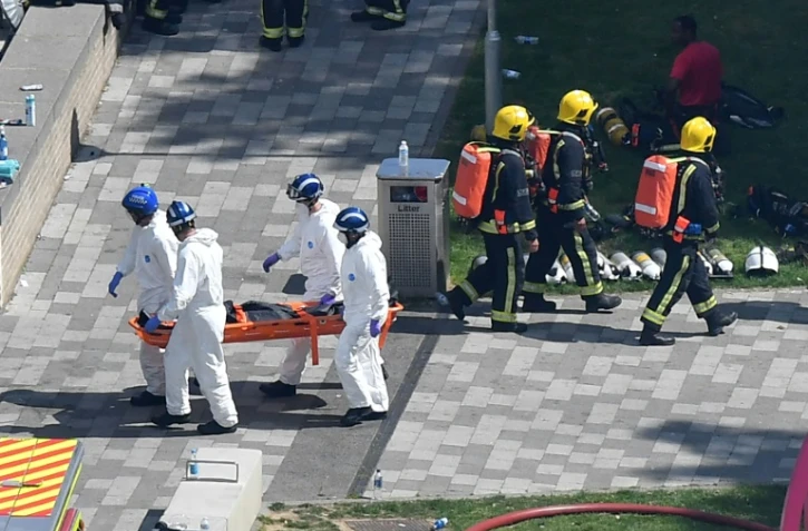 La police porte le corps d'une victime de l'incendie qui a ravagé dans la nuit de mardi à mercredi une tour de logements sociaux à Londres, le 14 juin 2017