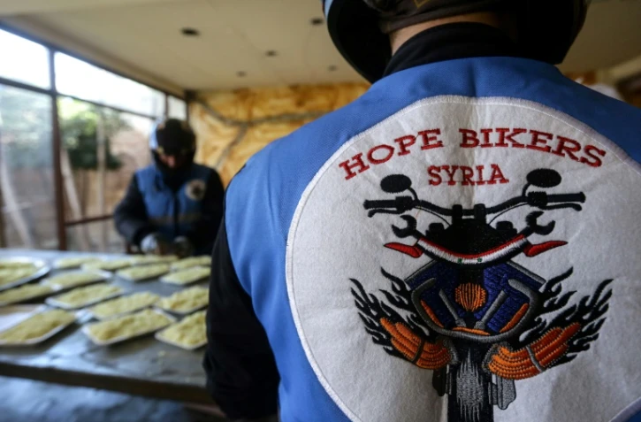 Des membres du club de motards "Hope Bikers Syria" préparent la distribution de repas aux personnes dans le besoin pendant le ramadan, le 25 mars 2024 à Damas, en Syrie