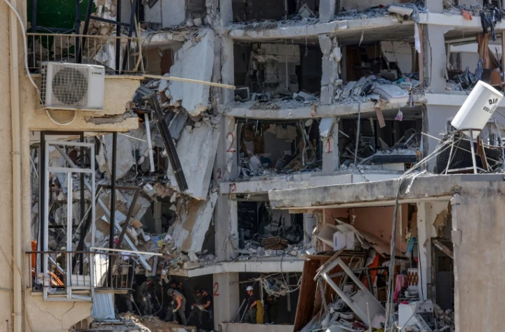 Des secouristes israéliens fouillent les décombres d'un bâtiment touché par des tirs de missiles iraniens dans la ville côtière de Bat Yam, au sud de Tel-Aviv, le 15 juin 2025