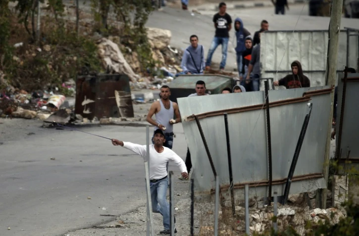 Des manifestants palestiniens jettent des pierres sur des soldats israéliens, dans le village de Sair, près d'Hébron en Cisjordanie, le 26 octobre 2015