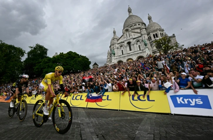 Le maillot jaune Tadej Pogacar et le Belge Wout Van Aert passent devant la basilique du Sacré-Cœur sur la Butte Montmartre, lors de la 21e et dernière étape du Tour de France, le 27 juillet 2025