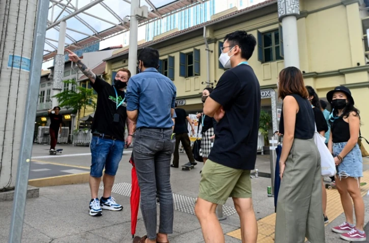 Bruce Mathieu (G) un ancien membre des sociétés secrètes, dirige une visite guidée sur les traces des triades dans le quartier financier de Singapour le 19 juin 2021