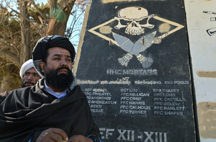 Le mollah Habibullah Mujahed, responsable taliban de la culture à Ghazni, se tient près d'un mur portant les noms de soldats américains, le 15 novembre 2021 à Ghazni, au sud de Kaboul