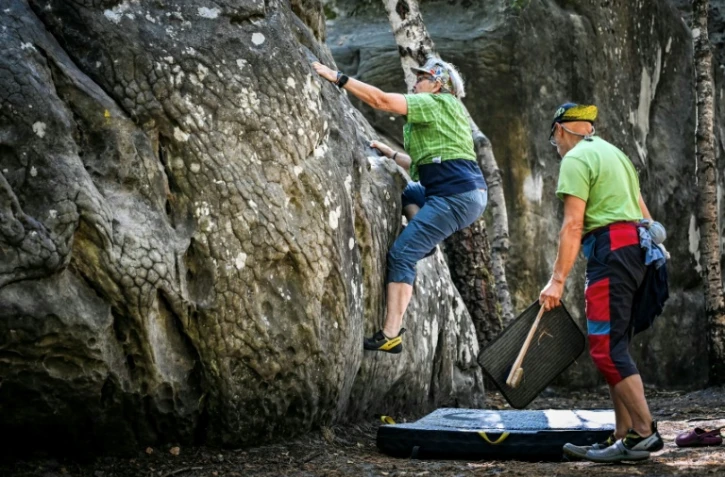Une femme escalade un rocher Ă Fontainebleau, au premier jour de la rĂ©ouverture au public du massif forestier partiellement dĂ©vastĂ© par les flammes en juillet, le 22 aoĂ»t 2026 prĂšs de Arbonne-la-forĂȘt, en Seine-et-Marne
