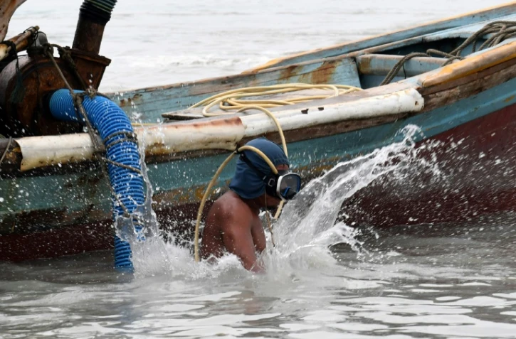 Un homme s'apprête à plonger pour remuer la vase et ramener de l'étain au large de l'île de Bangka, en Indonésie, le 10 novembre 2016