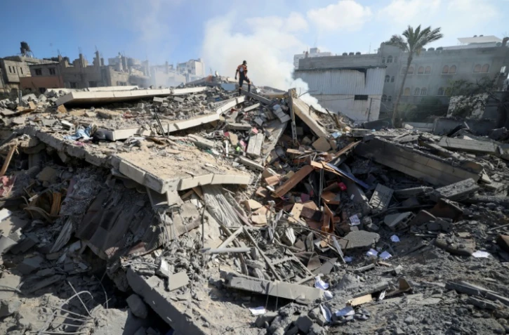 Un membre de la défense civile palestinienne au milieu des décombres d'un bâtiment de la ville de Gaza qui abritait la banque Intaj liée au mouvement Hamas qui contrôle la bande de Gaza, le 15 mai 2021