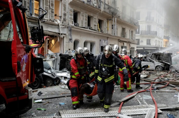 Des pompiers évacuent des blessés après une explosion rue de Trévise à Paris le 12 janvier 2018