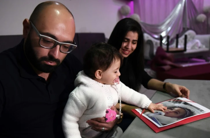 Sacha, 15 mois, touche une photo de sa soeur jumelle Marwa lors d'une conférence de presse de leur père Mohamed Bouchenafa, le 4 mars 2017 à Marseille
