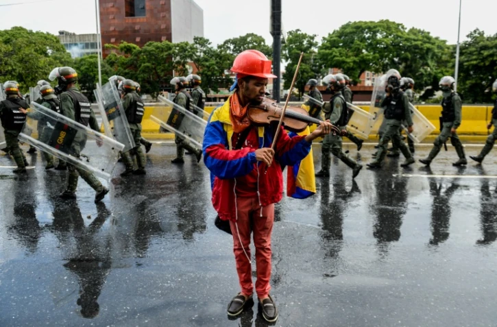 L'opposant Wuilly Arteaga joue du violon davant la police antiémeute, le 24 mai 2017 à Caracas, au Venezuela