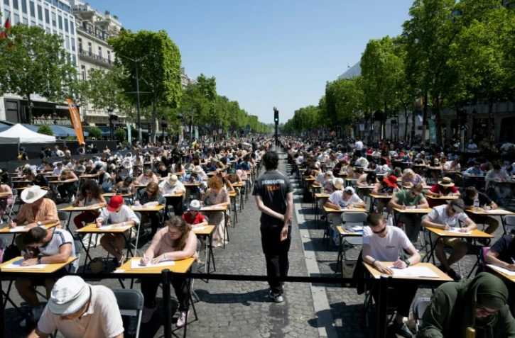 Des milliers de personnes de dix ans à 92 ans participent à une dictée géante sur l'avenue des Champs-Elysées à Paris, le 4 juin 2023 