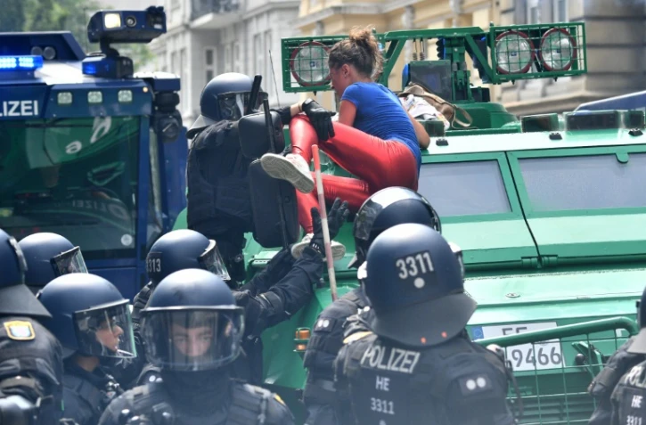 Des policiers tentent de faire descendre une manifestante anti-G20 grimpée sur un véhicule blindé de la police, le 7 juillet 2017 à Hambourg