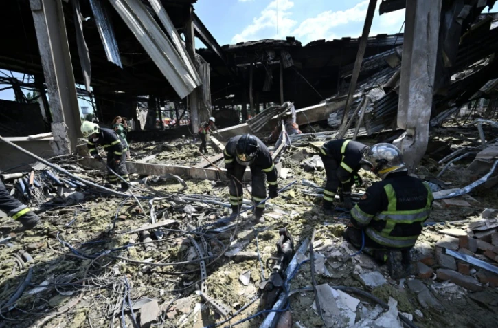 Des sauveteurs déblaient les décombres d'un centre commercial à Krementhouk, en Ukraine, le 28 juin 2022, au lendemain d'une frappe russe qui a fait au moins 18 morts, selon Kiev