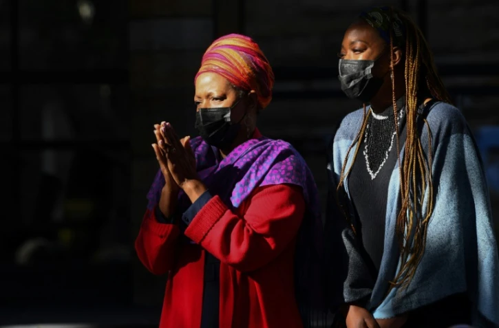 Mpho Tutu (G), fille de l'archevèque sud-africain et prix Nobel de la paix Desmond Tutu,  avec sa propre fille Nyaniso Burris, arrive à la cathédrale du Cap avec le cortège amenant le cercueil de son père, le 31 décembre 2021