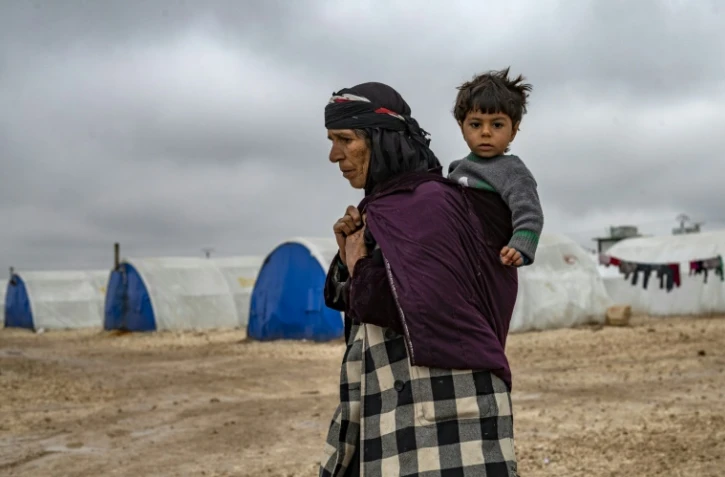 Une femme syrienne porte un enfant dans un camp pour déplacés, près de Hassaké, dans le nord-est de la Syrie en guerre, le 17 février 2020