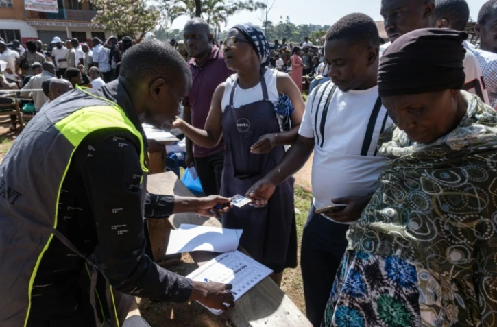 Des responsables de la Commission électorale vérifient les noms des électeurs sur le registre électoral avant leur vote à Kampala lors des élections générales, le 15 janvier 2026 en Ouganda