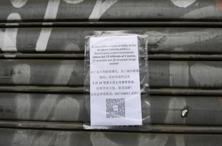 Une affiche annonce la fermeture d'un magasin en raison de l'épidémie de nouveau coronavirus en Italie, le 25 février 2020 dans le quartier chinois de Milan