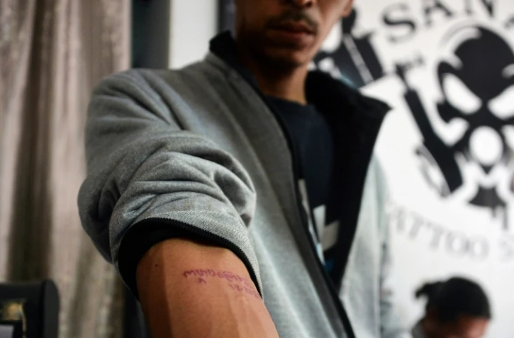 Un homme montre le 6 février 2021 à Naypyidaw, en Birmanie, son tatouage sur lequel on peut lire les paroles d'une chanson révolutionnaire: "Kabar Ma Kyay Bu"" ("Nous tiendrons jusqu'à la fin du monde"), en signe de protestation après le coup d'Etat