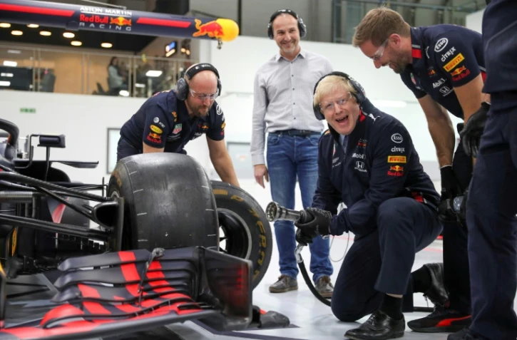 Le Premier ministre conservateur Boris Johnson change laroue d'une Formule 1 Red Bull, lors d'une visite dans le cadre de la campagne pour les législatives, à Milton Keynes au nord de Londres, le 4 décembre 2019