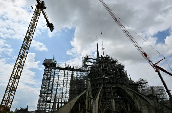 Une grue réinstalle la croix au sommet de la charpente de la cathédrale Notre-Dame, à Paris, le 24 mai 2024