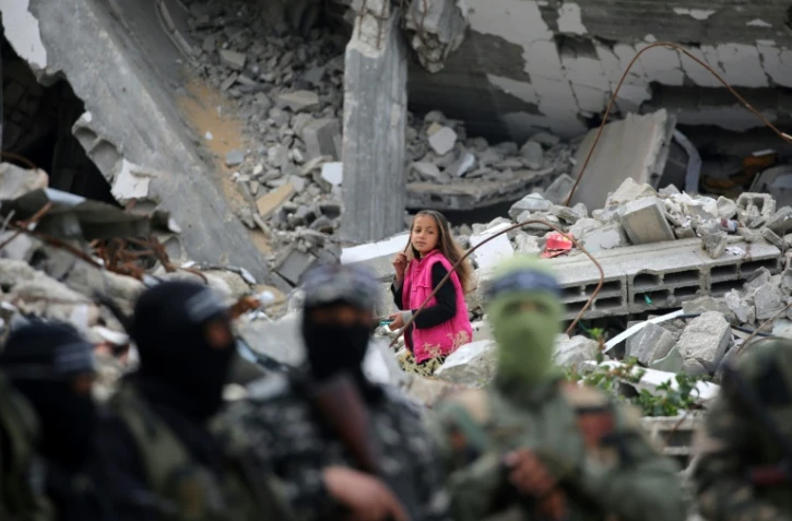 Un enfant passe derrière des combattants de la branche armée du Hamas qui assistent aux obsèques d'un haut commandant du Hamas, Marwan Issa, tué en mars 2024, à Bureij, dans le centre de la bande de Gaza, le 7 février 2025