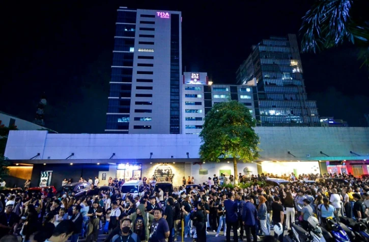 Les employés du centre d'appels surfent sur leurs téléphones portables alors qu'ils se rassemblent devant leur immeuble de bureaux après les secousses du tremblement de terre à Cebu, dans le centre des Philippines, le 30 septembre 2025
