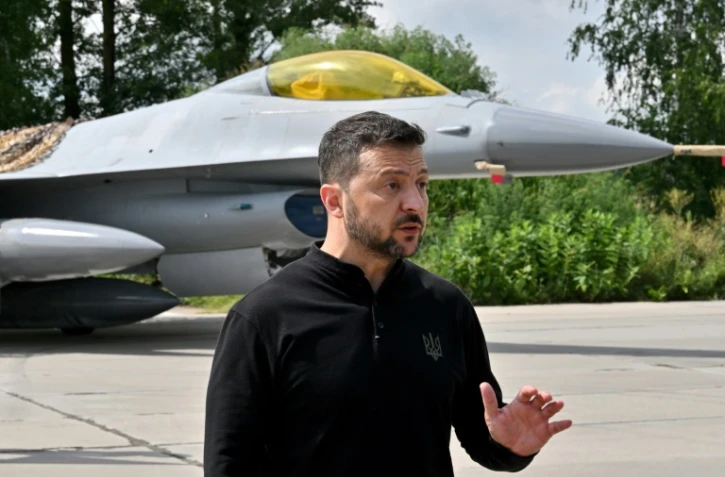 Le président ukrainien Volodymyr Zelensky devant un chasseur F-16 lors d'une cérémonie dans un lieu tenu secret en Ukraine, le 4 août 2024