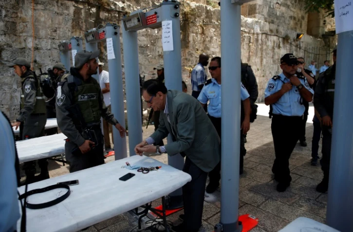 Un palestinien vide ses poches près du portique détecteur de métaux installé près de la porte des Lions, l'une des principales entrées de la Vieille ville de Jérusalem, le 16 juillet 2017