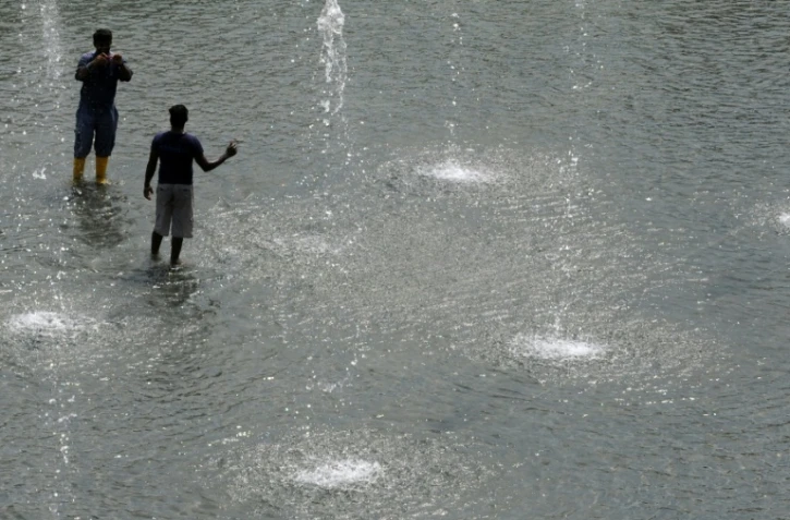 Des personnes se rafraichissent dans une fontaine lors de grosses chaleurs à Singapour, le 21 juin 2010