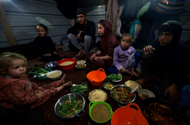 Une famille palestinienne rompt le jeûne au deuxième jour du ramadan dans un camp pour personnes déplacées à Rafah, dans le sud de la bande de Gaza, le 12 mars 2024