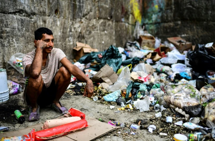 Un homme attend de trouver un peu de nourriture à côté d'un dépôt d'ordures, le 14 mars 2019 dans le quartier de Las Minas, à Caracas